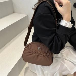 Brown nylon crescent tote bag with pleated design and wide adjustable shoulder strap
