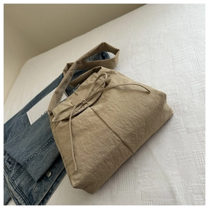 Khaki nylon crossbody bag with drawstring bow detail on a white fabric background