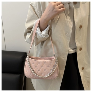 Detail of pink quilted baguette bag with pearl and metal chain accents for summer