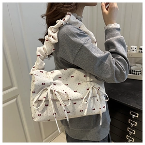 Detail of ruffle strap and floral bow pattern on cream canvas shoulder bag