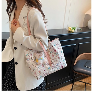 Detail of cartoon printed tote bag with pink leather strap and white plush rabbit charm