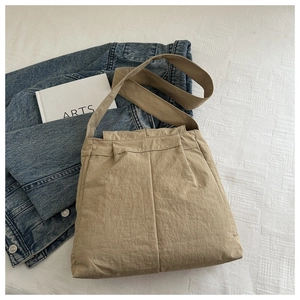 Detail of khaki nylon messenger bag with wide shoulder strap on denim jacket background