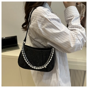 Detail of black quilted shoulder bag with elegant pearl and metal chain straps
