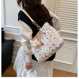 Detail of white tote bag with sweet cartoon prints, gold chain and plush bear charm