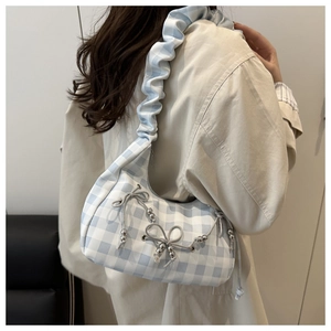 Detailansicht einer blauen Gingham-Schultertasche mit Schleifen und gerafftem Trageriemen