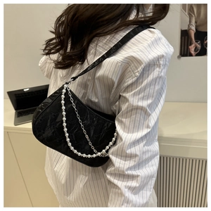 Detail of black crossbody bag with double pearl and metal chain on model
