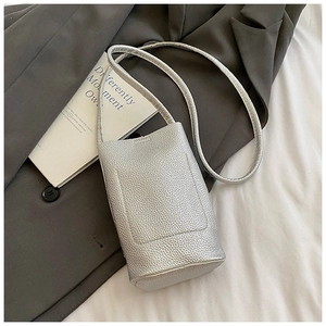 Detail of silver lychee pattern mini crossbody bag on dark gray suit jacket