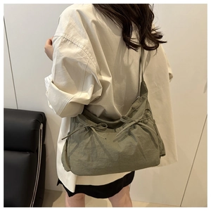 Detail of olive green nylon crossbody bag with stylish bow drawstring and pleated design