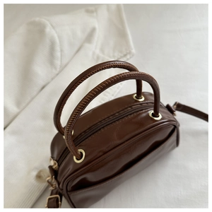 Detail of vintage brown PU leather boston bag with unique stitched handle and gold hardware