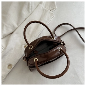 Detail view of brown patent leather mini bag showing interior space for smartphone