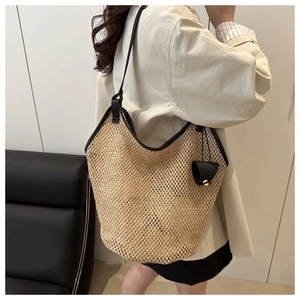 Close-up of woven straw tote bag with black leather trim and long shoulder straps
