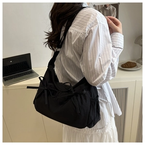 Detail of black nylon crossbody bag featuring cute bow knots and elastic side pocket