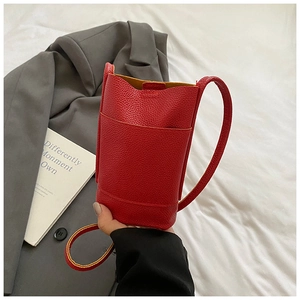 Detail of red pebbled leather crossbody bucket bag with front pocket and slim strap