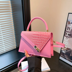 Rosa Handtasche mit Krokodilprägung und goldenem Drehverschluss am minimalistischen Fenster