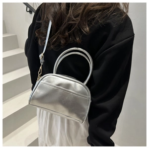 Detail of silver metallic handbag featuring smooth leather texture and adjustable strap