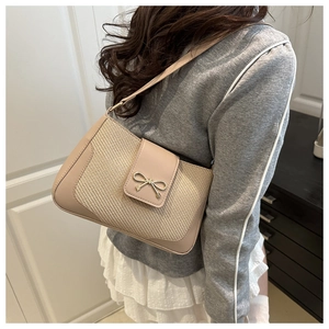 Détail du sac selle tissé beige avec une boucle nœud dorée élégante et bandoulière