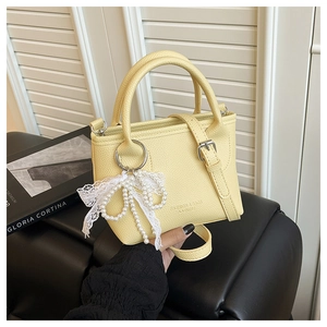 Détail du sac à main jaune en cuir avec pendentif en dentelle et perles de nacre