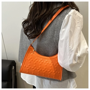 Detail of orange quilted baguette bag showing diamond texture and slim shoulder strap