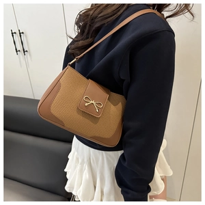 Vue détaillée du sac à bandoulière en cuir tressé marron avec boucle nœud doré sur un mannequin