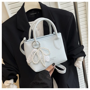 Détail du sac à main bleu clair avec breloque perle et dentelle et texture litchi