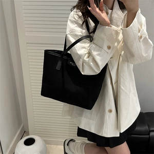 Minimalist black canvas tote bag with slim leather handles for stylish daily commuting