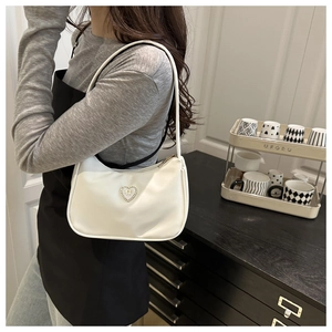 Detail of white leather half-moon shoulder bag featuring a silver heart buckle with rhinestones