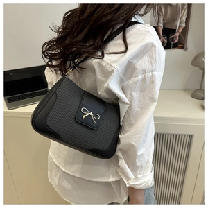 Détail d'un sac bandoulière noir avec boucle dorée dans un décor de style de vie