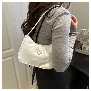 Close-up of white leather underarm bag with a crystal heart and golden bow detail