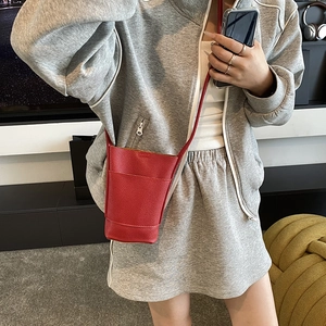 Red pebbled leather mini crossbody phone bag with minimalist bucket style on a female model