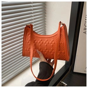 Detailed view of orange quilted faux leather texture on minimalist shoulder bag