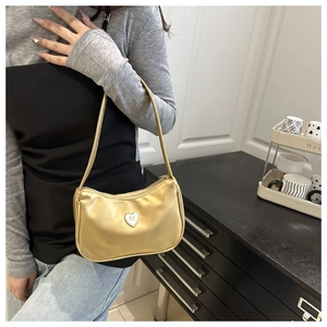 Detailed view of gold metallic shoulder bag featuring heart logo and soft pleated texture