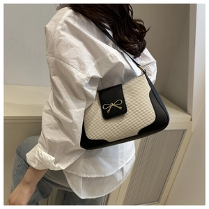 Détail d'un sac à bandoulière tissé crème avec cuir noir et fermoir noeud doré
