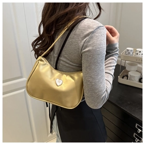 Detail of champagne gold shiny leather underarm bag featuring a crystal heart ornament