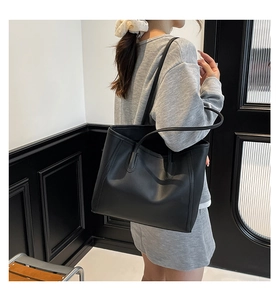Detailed view of black minimalist tote bag with slender straps and matte texture finish