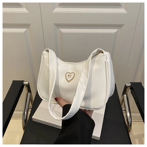 Detail of white crescent shoulder bag featuring a gold heart rhinestone buckle closure