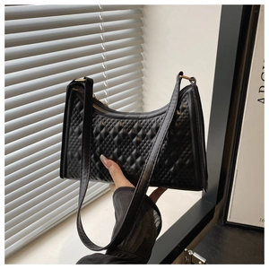 Detail of black quilted shoulder bag with textured pattern and sleek zipper closure