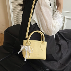 Sac seau chic jaune pâle en cuir avec breloque dentelle et bandoulière élégante