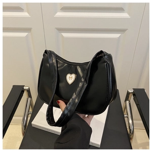 Detail of black crescent shoulder bag featuring a pearl heart and golden bow ornament