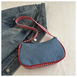 Dettaglio della borsa a spalla in denim azzurro con cuciture in tessuto a quadri rossi e bianchi