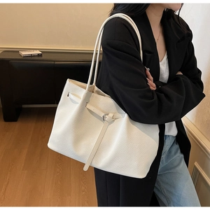 Detailed view of white embossed tote bag with adjustable strap and metal buckle detail