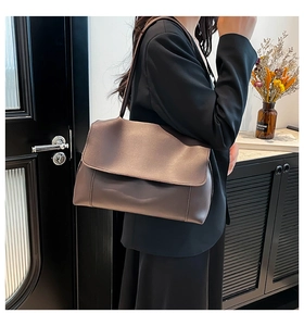 Detail of coffee brown PU leather shoulder bag with lychee texture and flap closure