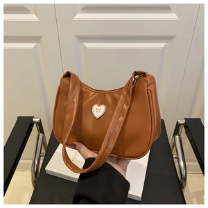 Detail of a brown hobo bag with gold heart bow hardware and double shoulder straps