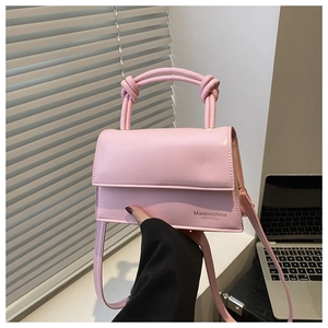 Detail showing pink rectangular handbag with knot handle design and adjustable shoulder strap