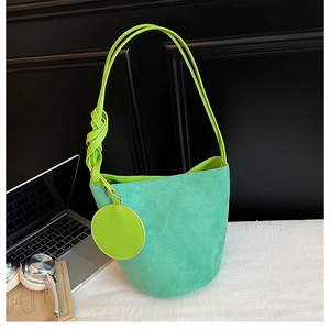 Detail of teal suede bucket bag with neon green leather strap and side circular charm