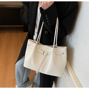 Detail view of cream white tote bag with textured faux leather and metal buckle detail