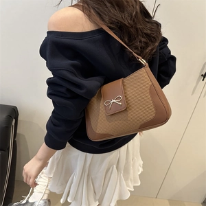 Sac à bandoulière en cuir tressé marron avec boucle nœud doré porté par un modèle