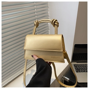 Detail view of champagne gold crossbody bag with a knotted handle and metallic finish