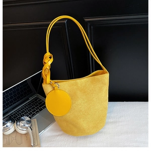 Close-up of bright yellow suede bucket bag with hand-woven knotted shoulder strap detail