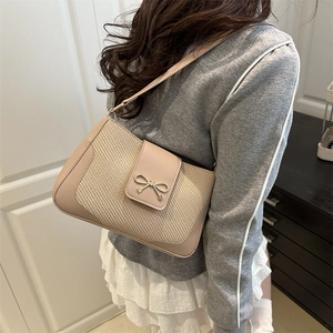 Sac bandoulière minimaliste en beige tissé avec nœud doré, porté par un mannequin