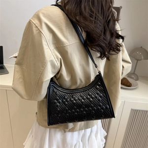 Chic black underarm bag with embossed rhombic texture shown on a female model
